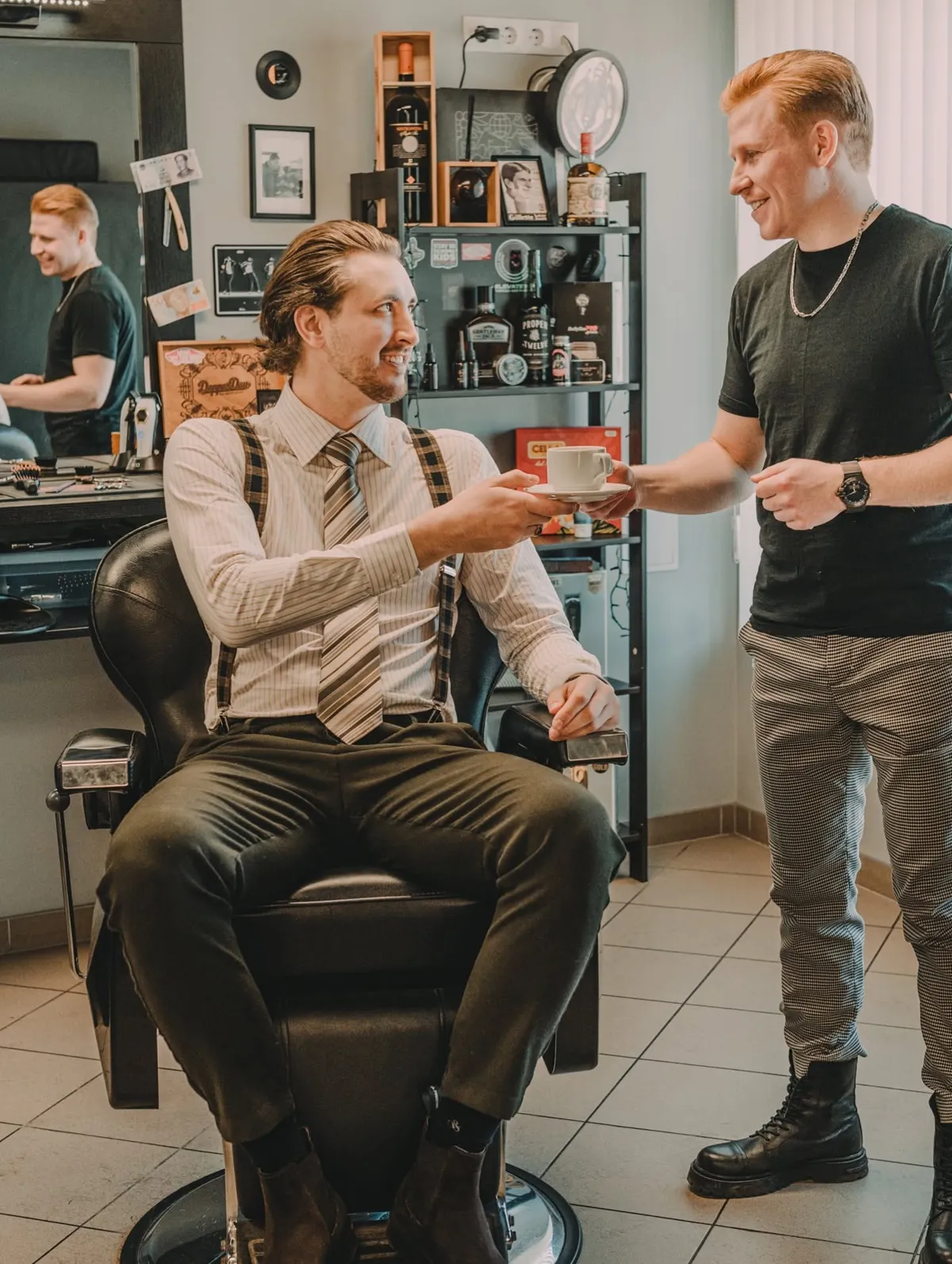 Meistars pasniedz klientam kafijas tasi bārbera krēslā